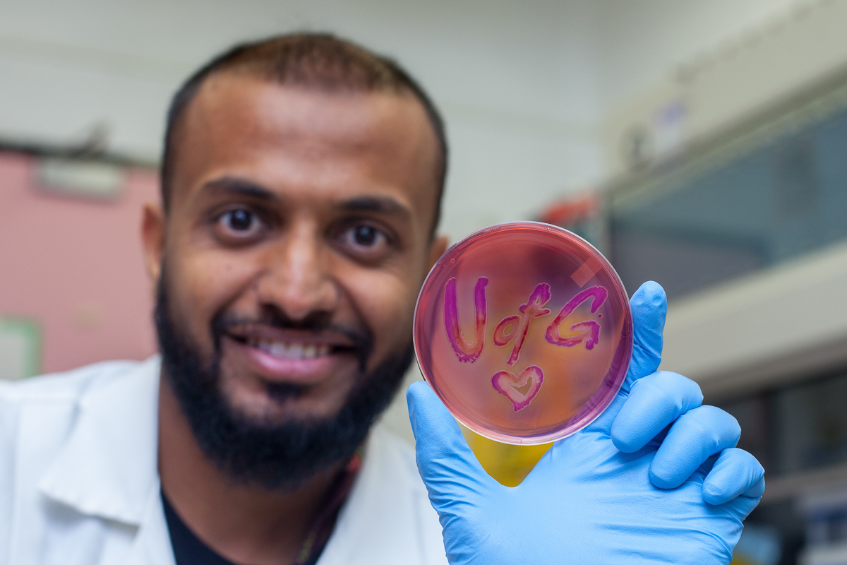 Student holds up U of G logo in a science lab