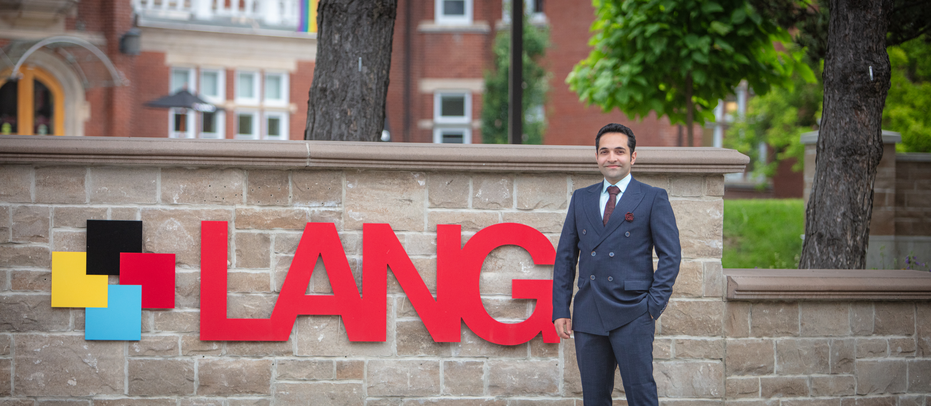 Lang MSc Management grad student, Ario Moradman standing in front of the Lang sign