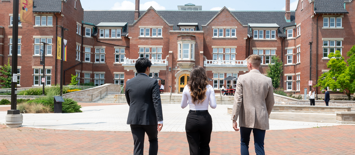 3 people walking towards the Lang building at the University of Guelph