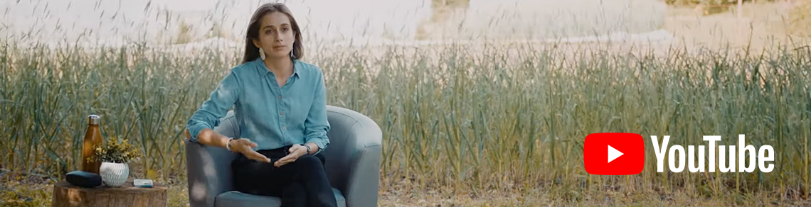 Margarita Fontecha, U of G Rural Studies PhD student sits on a chair beside a field of corn