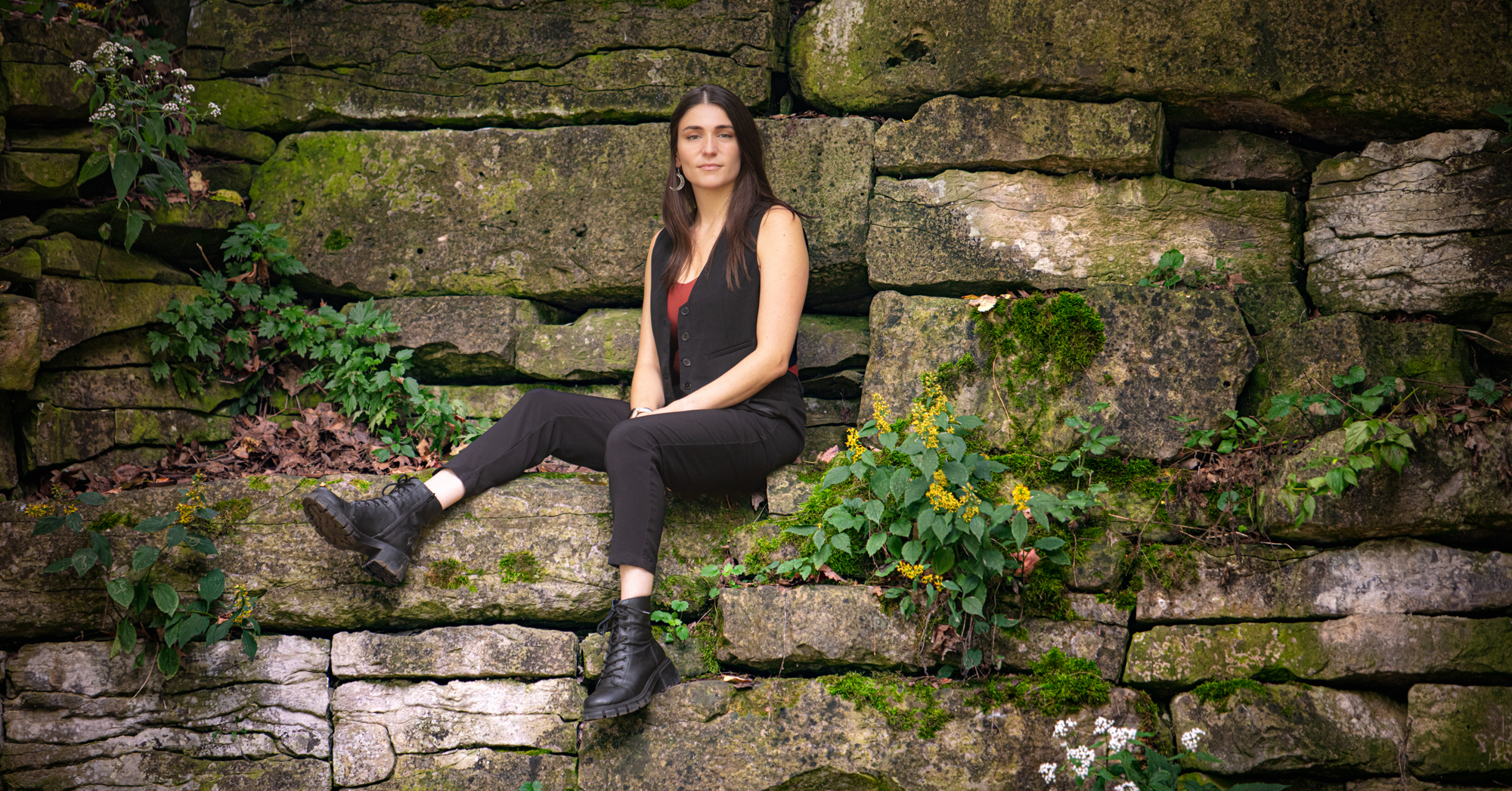 Portrait of Megan Lalli sitting on a cliff face.