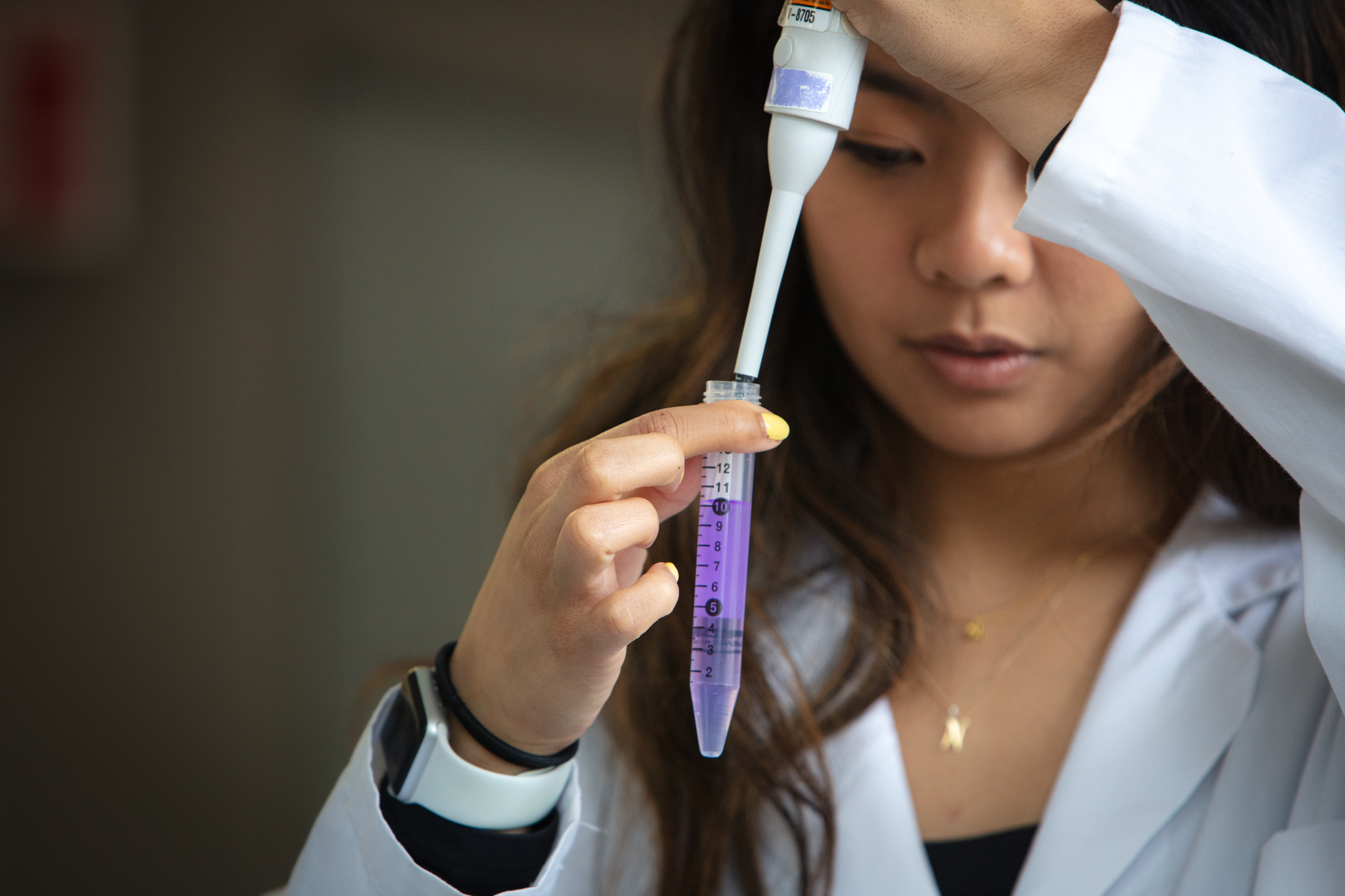 U of Guelph Master of Biomedical Sciences student, Nicole Prudenciano pipetting a purple solution in a lab