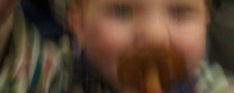 Close up of a young child with a pacifier in its mouth, blurred. 